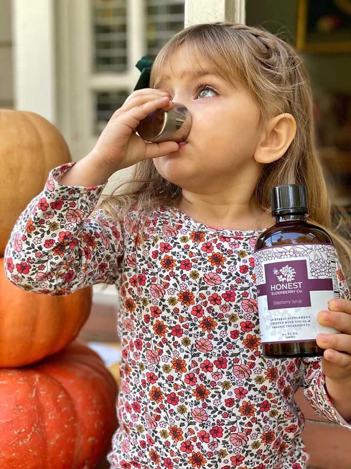 young girl drinking honest elderberry syrup